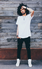 Portrait young handsome fashion bearded afro hair model black man in urban. Rest and relax. Dressed in a white t-shirt. Afro Hairstyle. Srteetstyle. Old wood boards on background.