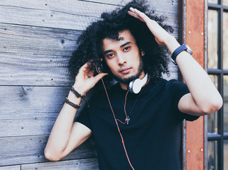 Close up portrait young African American man with an afro hairstyle as DJ. Headphones and red...