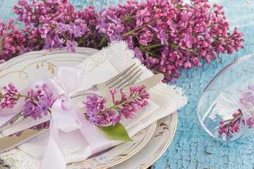 Tableware and silverware with violet lilac on the wooden background