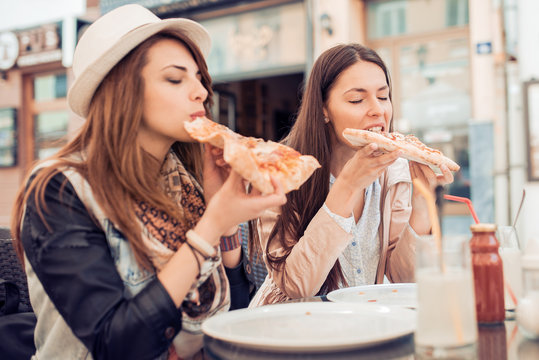 Two young women eating pizza