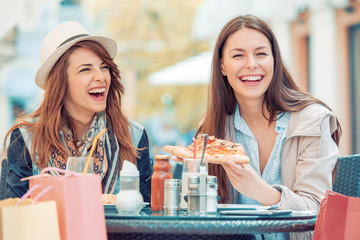 Two young women eating pizza