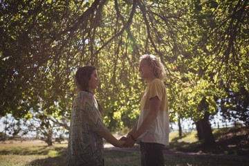 Naklejka premium Side view of couple holding hands while standing on field