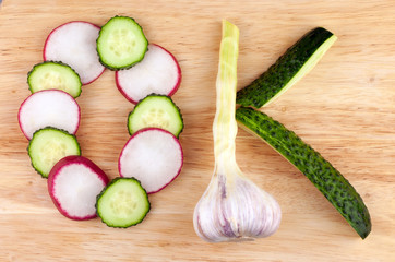 The word OK, made from circles of red radish, cucumbers and a head of garlic on a wooden background