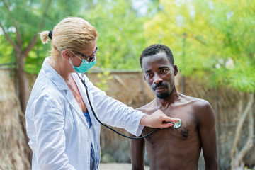 Caucasian woman doctor listening the hearth beat and breathing of sick black African man