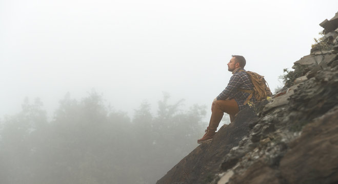 Male Tourist On Top Of Mountain In Fog In Autumn