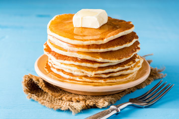 Pancakes with butter and honey on blue wooden table.