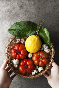 Organic products in a wicker basket. Fresh ripe tomatoes and quail eggs and lemon with leaves. healthy harvest