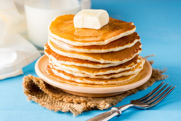 Pancakes with butter and honey on blue wooden table.
