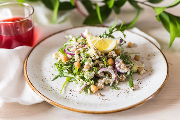 Racy salad with chickpea, arugula, pearl barley, onion and avocado on plate