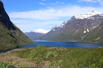 A beautiful spring day with snow on the mountain peaks, blue sky and green hills in Loen in Stryn.
