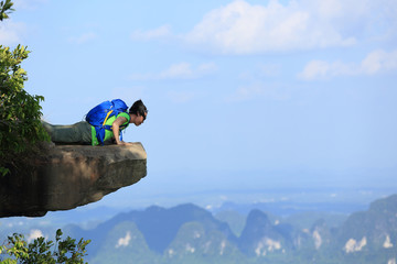 successful woman hiker looking down on mountain peak cliff