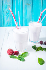Homemade milkshake with mint and berry on white wooden table