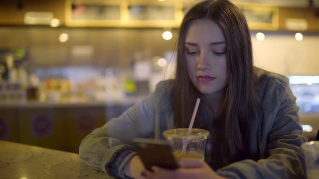 Closeup Of Girl Texting On Smart Phone, Next To Her Friend, At A Coffee Shop