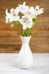 Flowers in a ceramic vase. Daisies and lilies. Vertical shoot.
