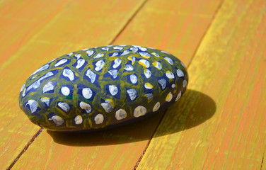 Hand decorated painted stone on yellow gold background