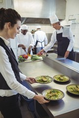 Waitress taking food dishes from order station