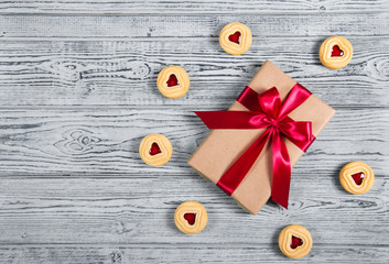 Gift box with satin bow and cookies with marmalade in the shape of heart. A romantic gift. Present on a gray background. Top view.