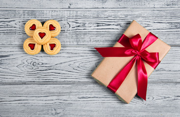 Gift box with satin bow and cookies with marmalade in the shape of heart. A romantic gift. Present on a gray background. Top view. Flat lay