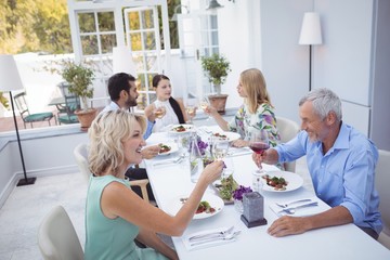 Obraz premium Group of friends toasting glasses of wine during meal