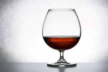 glass of brandy and chocolate piecesa lone glass of brandy, half empty, half full. abstraction, the concept of loneliness, alcoholism