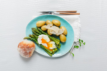 Light spring lunch on the plate. Fried asparagus, fresh potatoes and poached egg with parmesan cheese. healthy food.