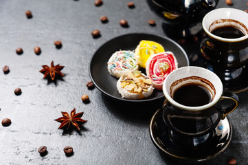 Cup of coffee with turkish delight on black stone background