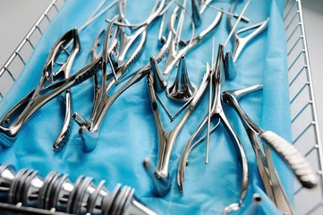  ENT Instruments closeup - nasal mirror, probes, cannulas for washing, nasopharyngeal mirror, ear watering can on a blue background