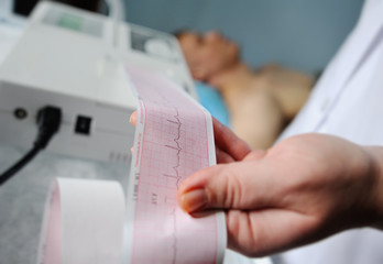 Electrocardiogram, ecg in hand. Clinic cardiology heart rhythm and pulse test closeup. Cardiogram printout. - obrazy, fototapety, plakaty