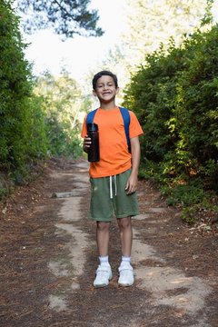 Boy with backpack and water bottle standing on the path