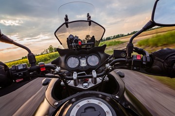 Fototapeta premium Mężczyzna jedzie motocyklem na wiejskiej drodze asfaltowej