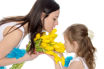 Mother and daughter smelling yellow tulips.