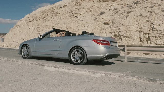 Happy blonde with man driving in the cabriolet