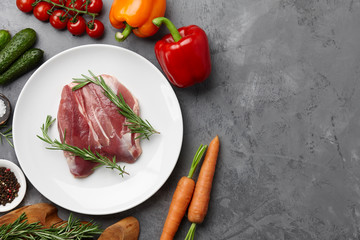 Raw duck breast, fresh vegetables, herbs and spices on gray stone background, copyspace
