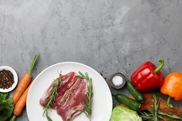 Raw duck breast, fresh vegetables, herbs and spices on gray stone background, copyspace