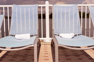 Fototapeta na wymiar Blue Chairs On A Sun Deck By The Pool And Lake