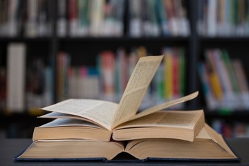 Stack of books on table against shelf