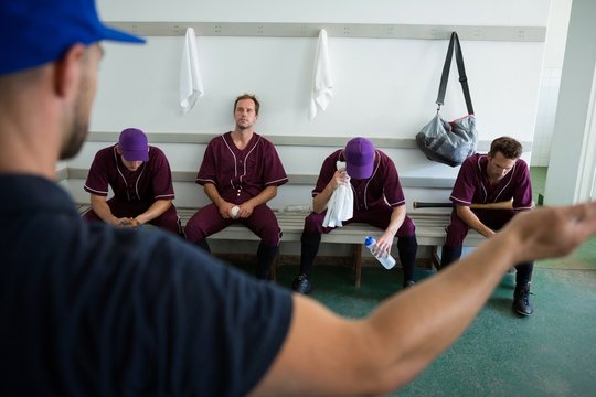 Rear view of coach discussing with baseball team - Powered by Adobe