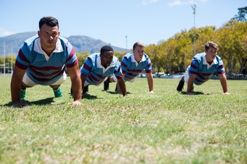 Obraz premium Confident rugby players doing push up at field