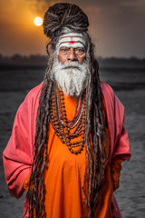 Portrait of sadhu standing with sunrise behind him, Varanasi, India.