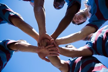 Low angle view of rugby team holding hands