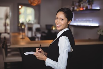 Smiling waitress writing order on notepad