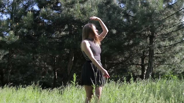 The young woman is dancing in the background against the forest