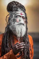 Portrait of sadhu standing with sunrise behind him, Varanasi, India.