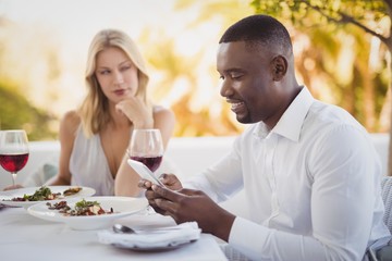 Man ignoring bored woman while using mobile phone