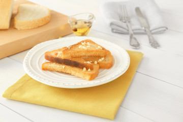 Plate with tasty garlic French bread slices on wooden table