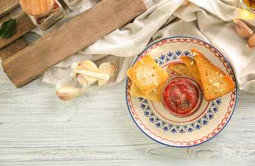 Plate with tasty garlic French bread slices on wooden table