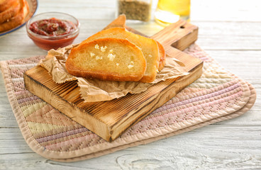 Tasty garlic French bread slices on wooden table