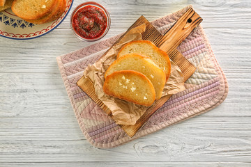 Tasty garlic French bread slices on wooden table