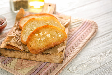 Tasty garlic French bread slices on wooden table