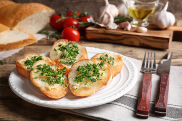 Tasty bread slices with garlic and herbs on plate